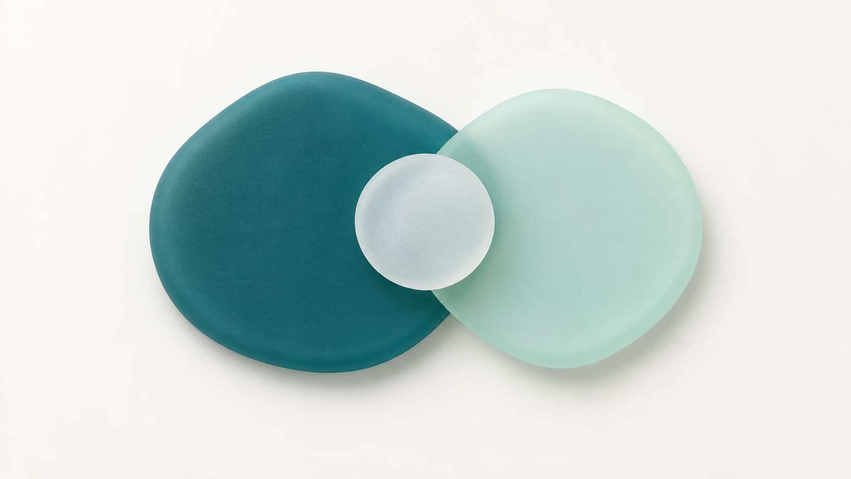 Two large overlapping matte pebble shapes in deep teal and pale mint with a small cloudy white disc