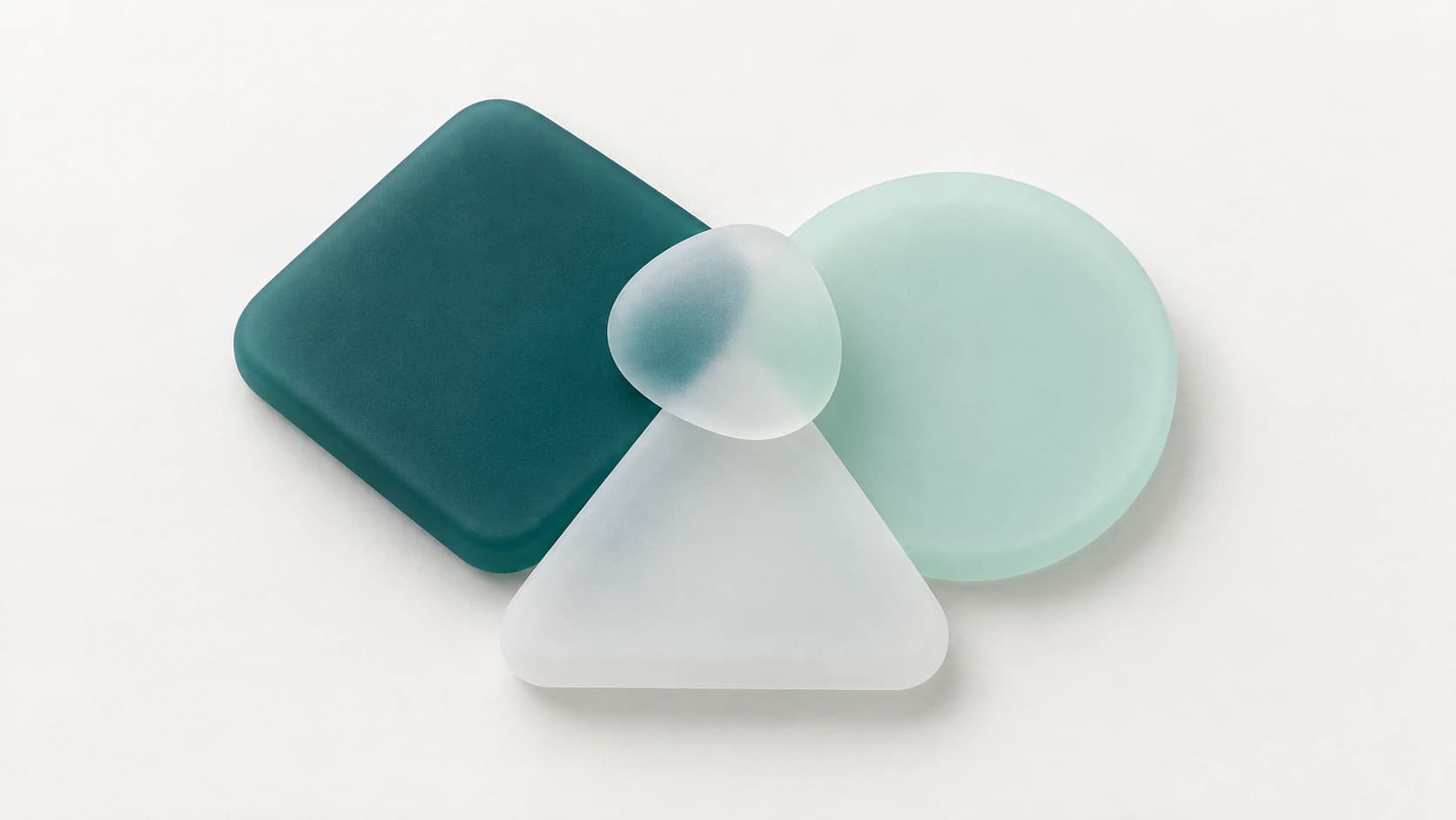 A teal rounded square, a pale mint circle and a white triangle in matte rubber with a small frosted pebble on top